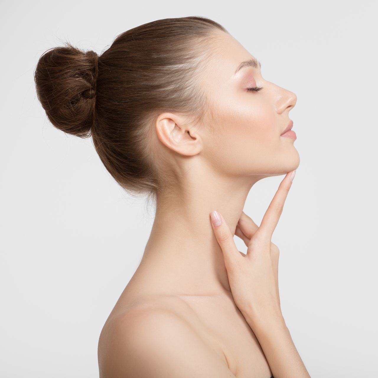 Femme aux cheveux bruns relevés en chignon, de profil, les yeux fermés.