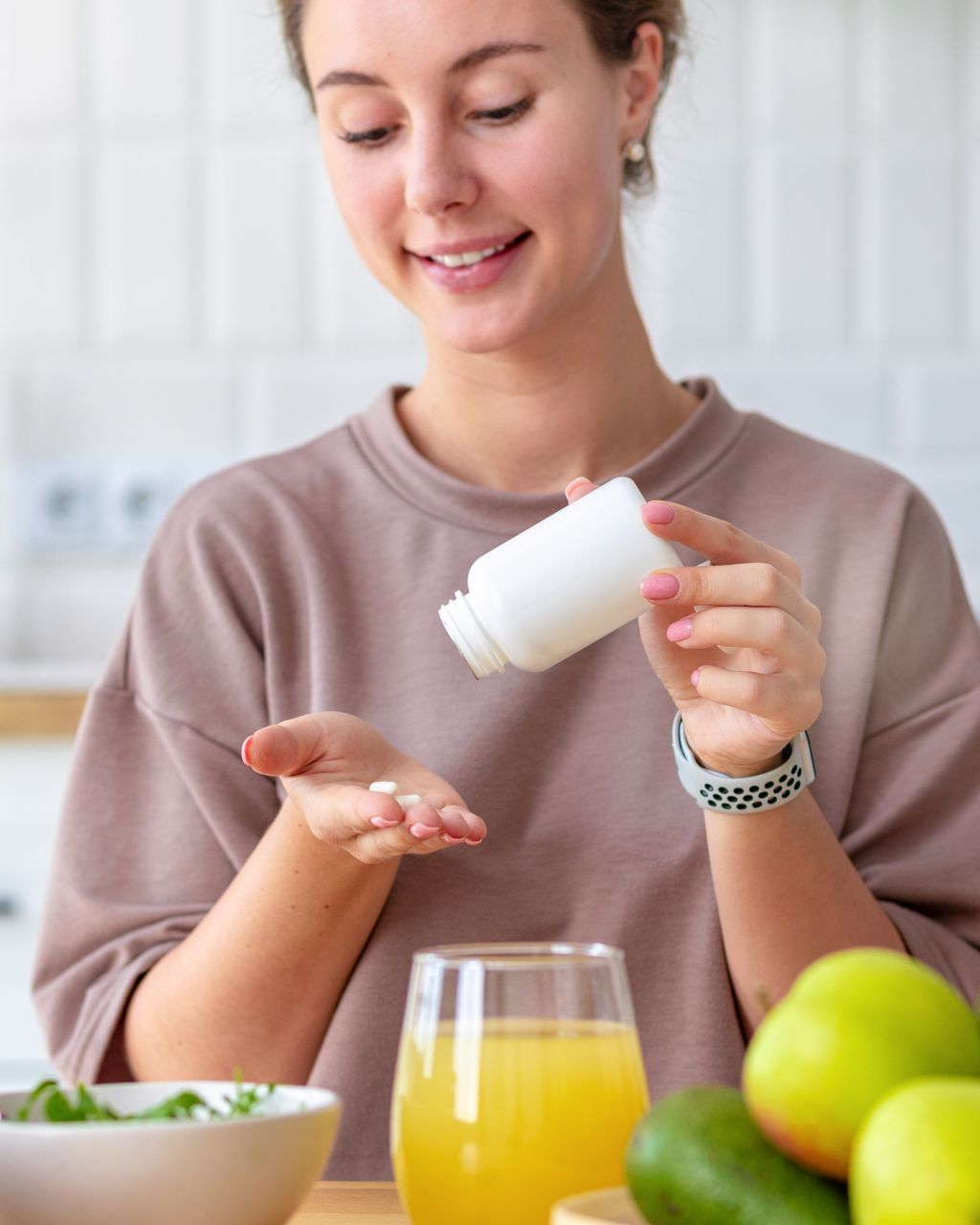 Une femme verse des pilules d'un flacon blanc dans sa paume.