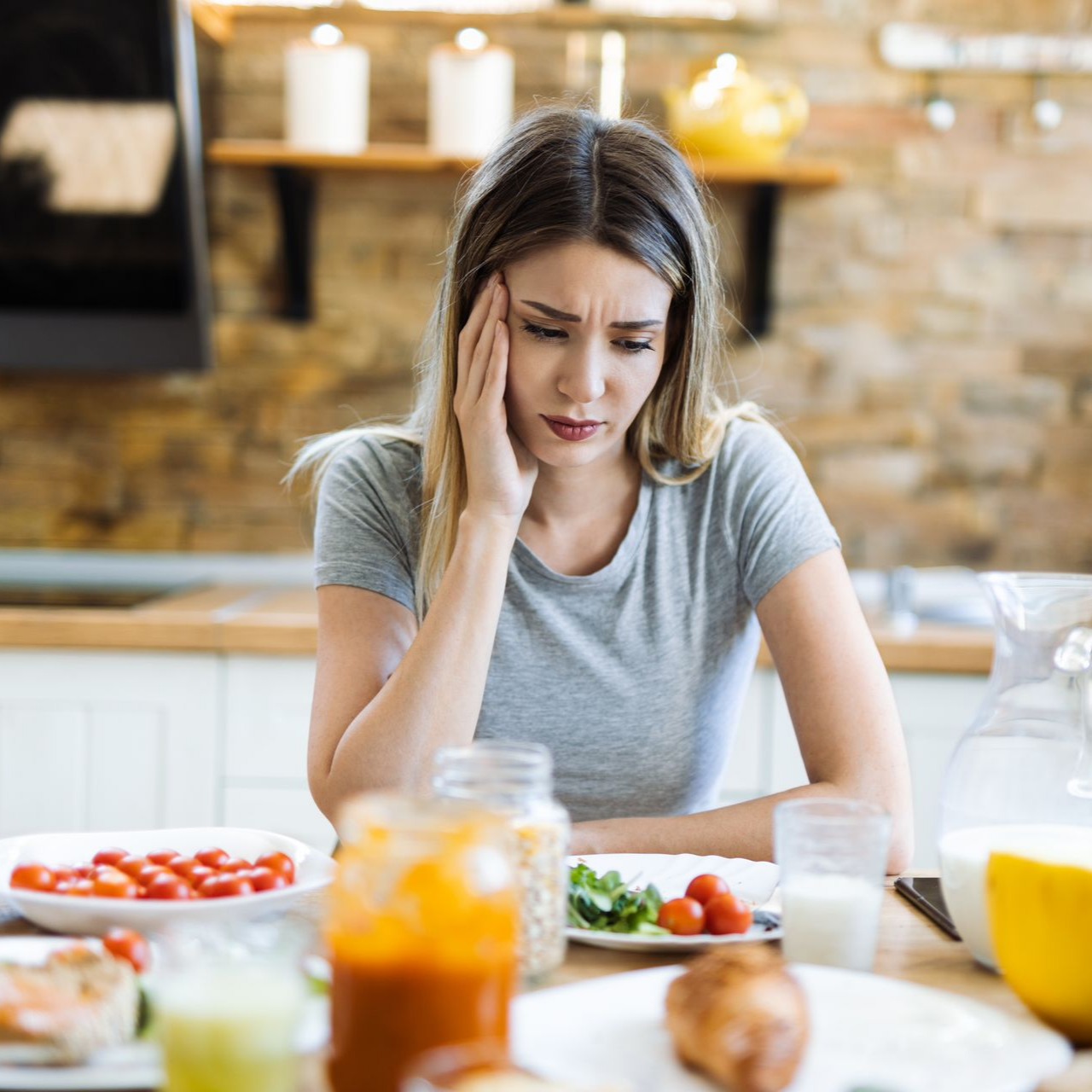 Une femme est assise à une table avec de la nourriture et des boissons disposées sur la table.