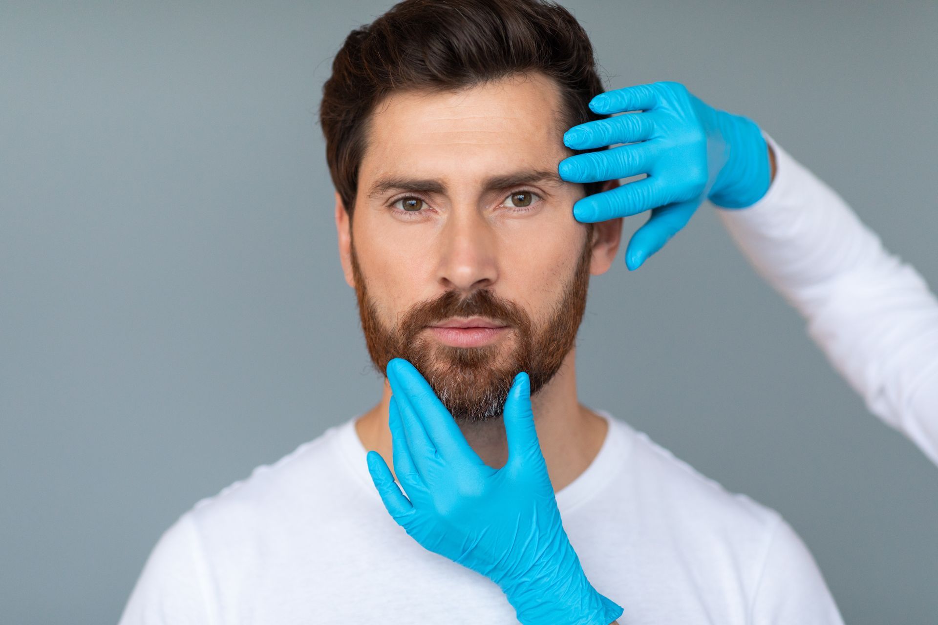 Le visage d'un homme est examiné par un médecin portant des gants bleus.