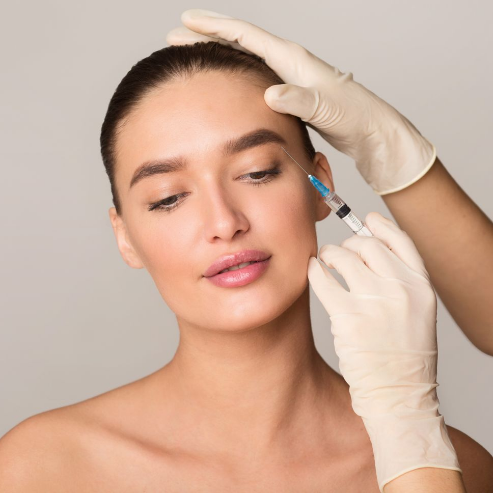 Personne recevant une injection au niveau du sourcil, des mains gantées tiennent une seringue.