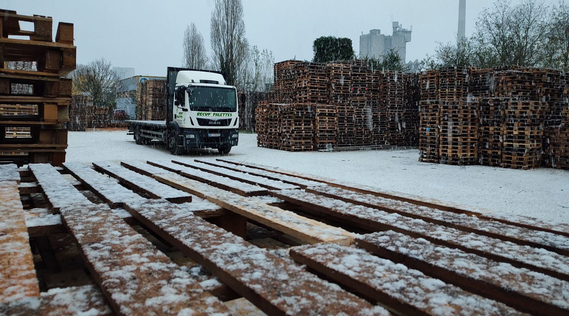 Des palettes en bois recouvertes de neige avec un camion pour le transport