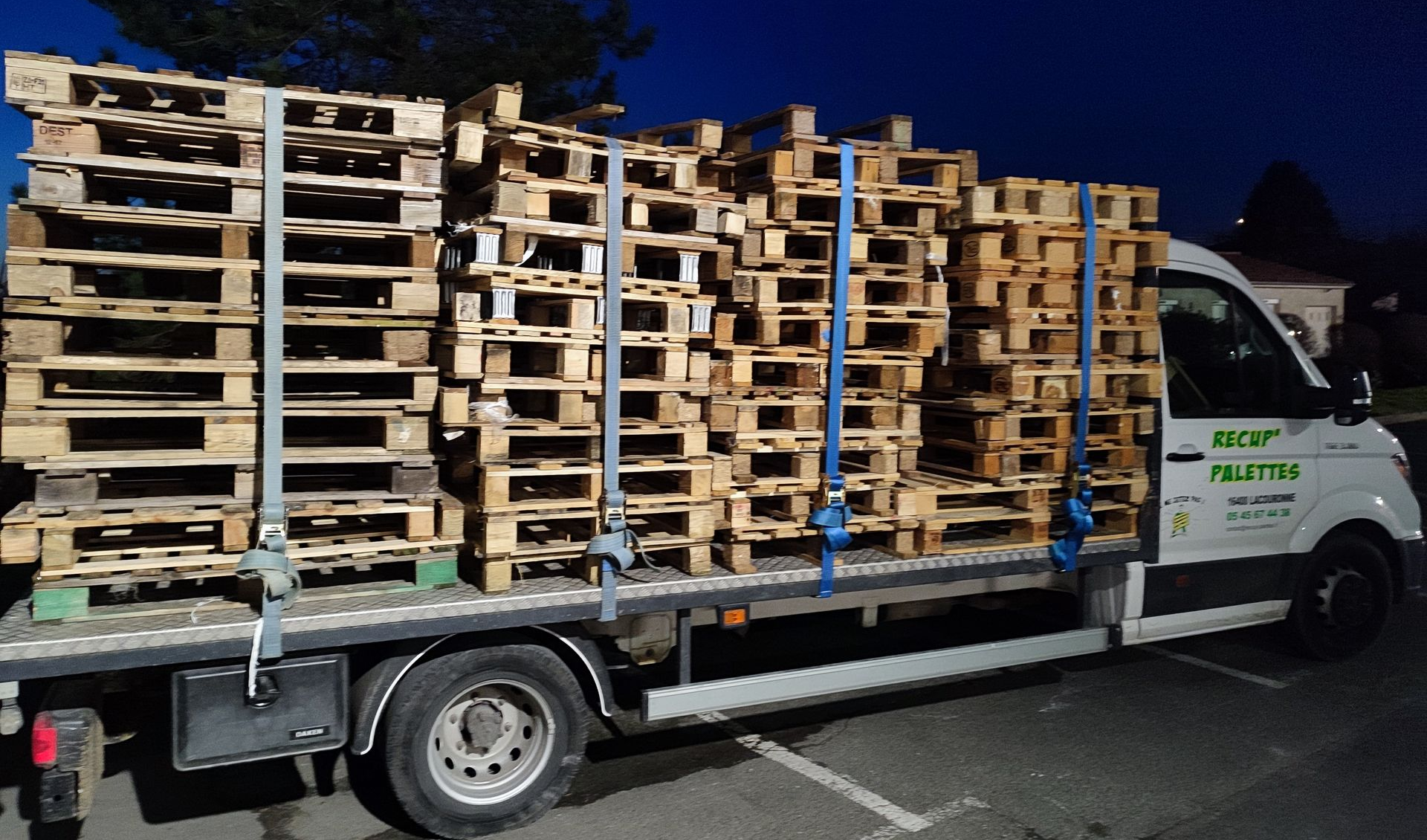 Des palettes en bois sont transportées par un camion la nuit