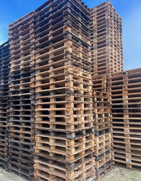 Une grande quantité de palettes en bois empilées en colonnes verticales