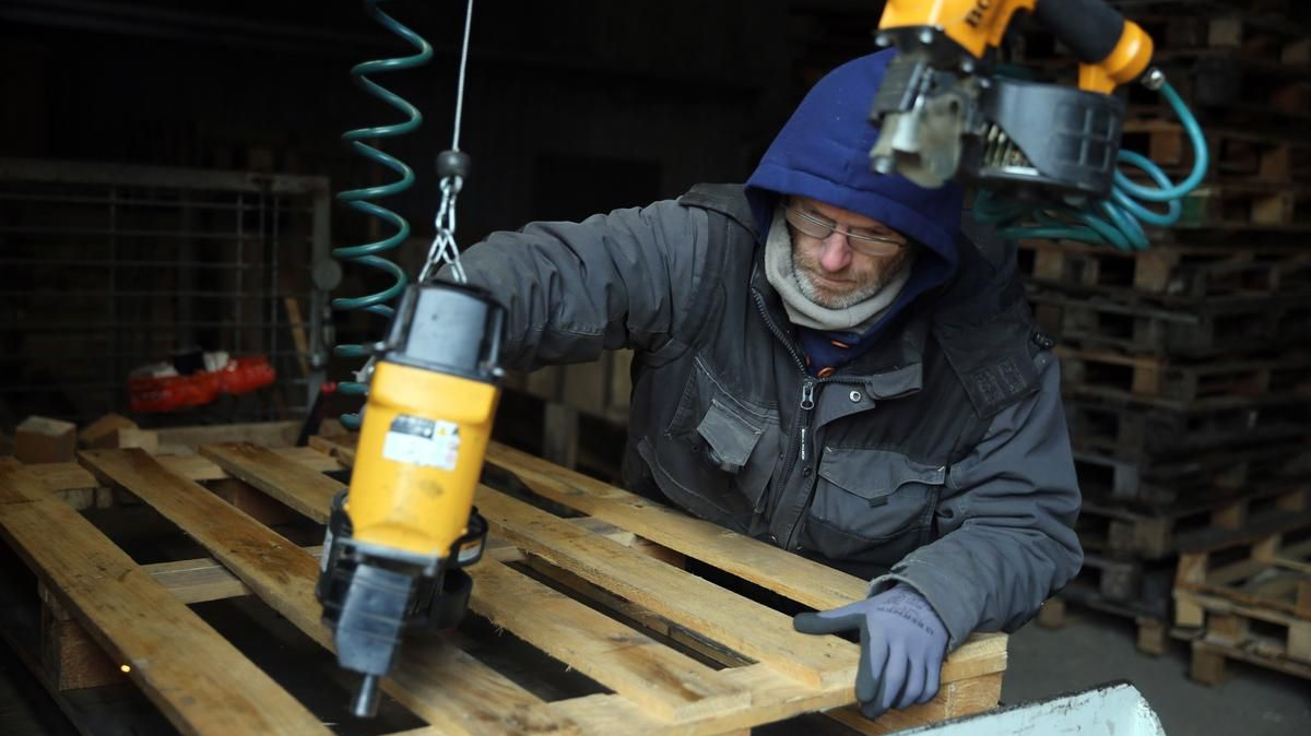 Un monsieur répare une palette en bois