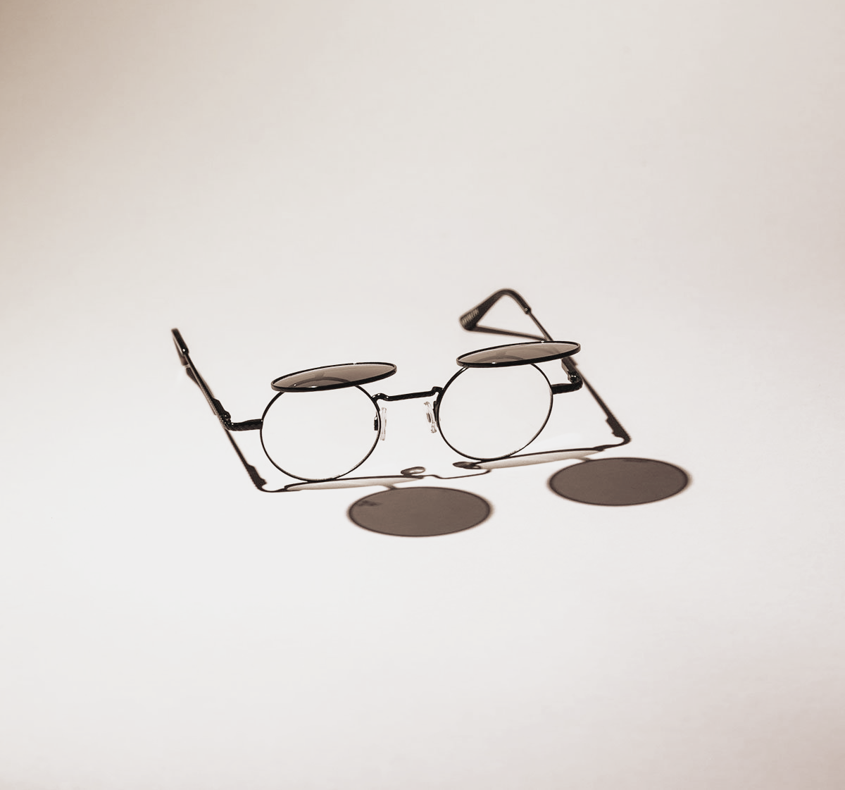 Les lunettes à monture métallique et verres circulaires projettent une ombre sur une surface claire.