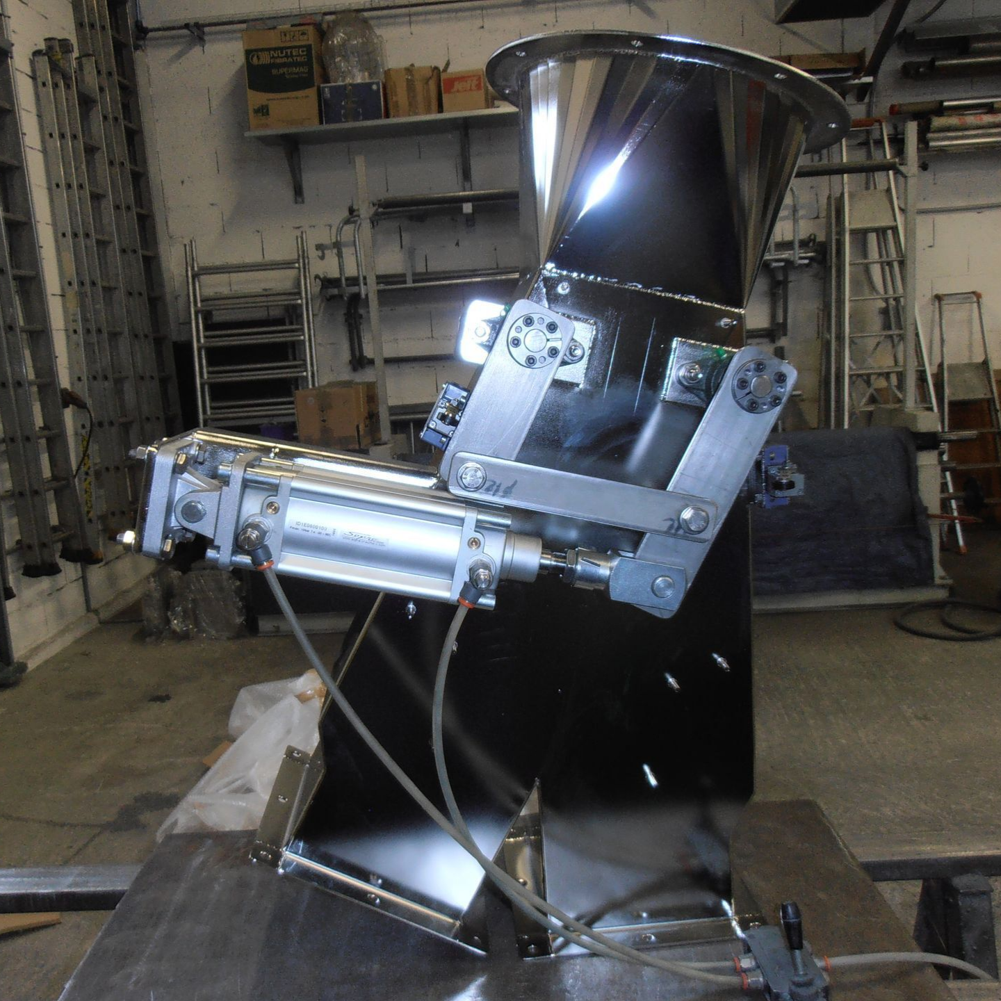 Trémie industrielle en acier inoxydable avec vérin pneumatique.