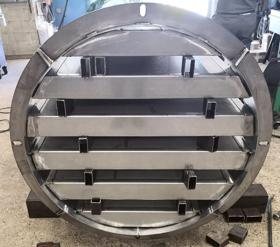 Crépine industrielle en acier inoxydable, circulaire avec chicanes internes, en configuration atelier.