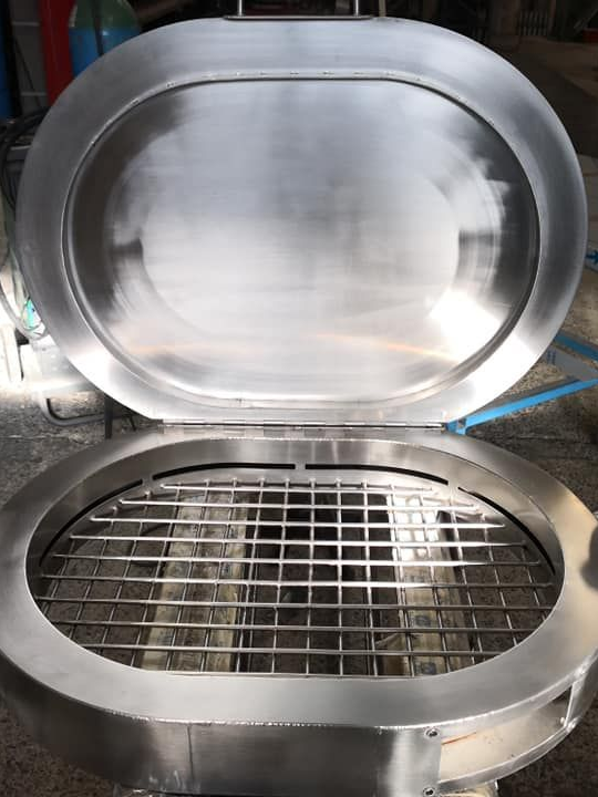 Gril ovale en acier inoxydable avec couvercle ouvert, exposant la grille de cuisson.