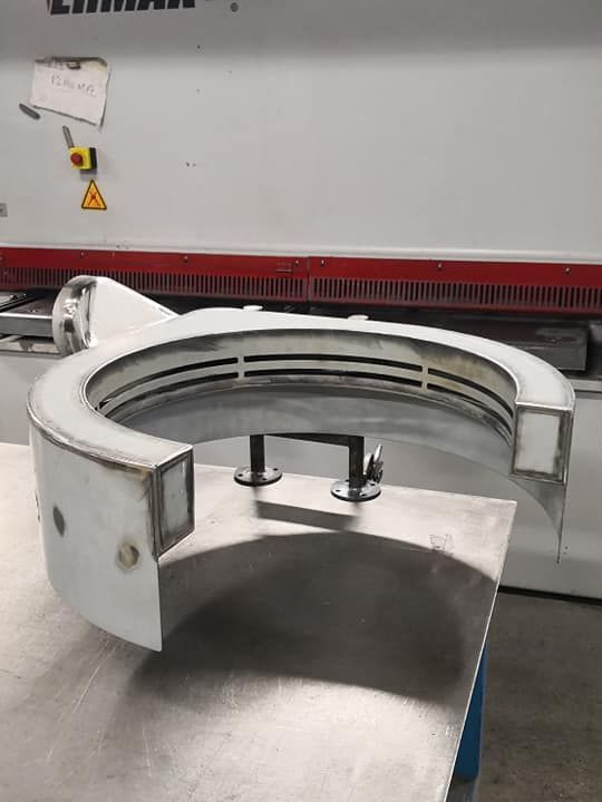 Pince circulaire en métal blanc sur une table en métal avec une machine industrielle rouge et blanche en arrière-plan.