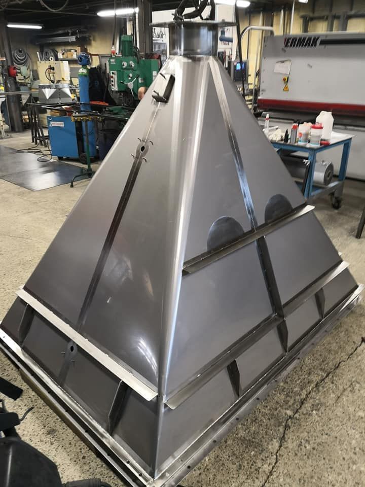 Une grande structure pyramidale en métal dans un atelier, probablement destinée à un usage industriel.