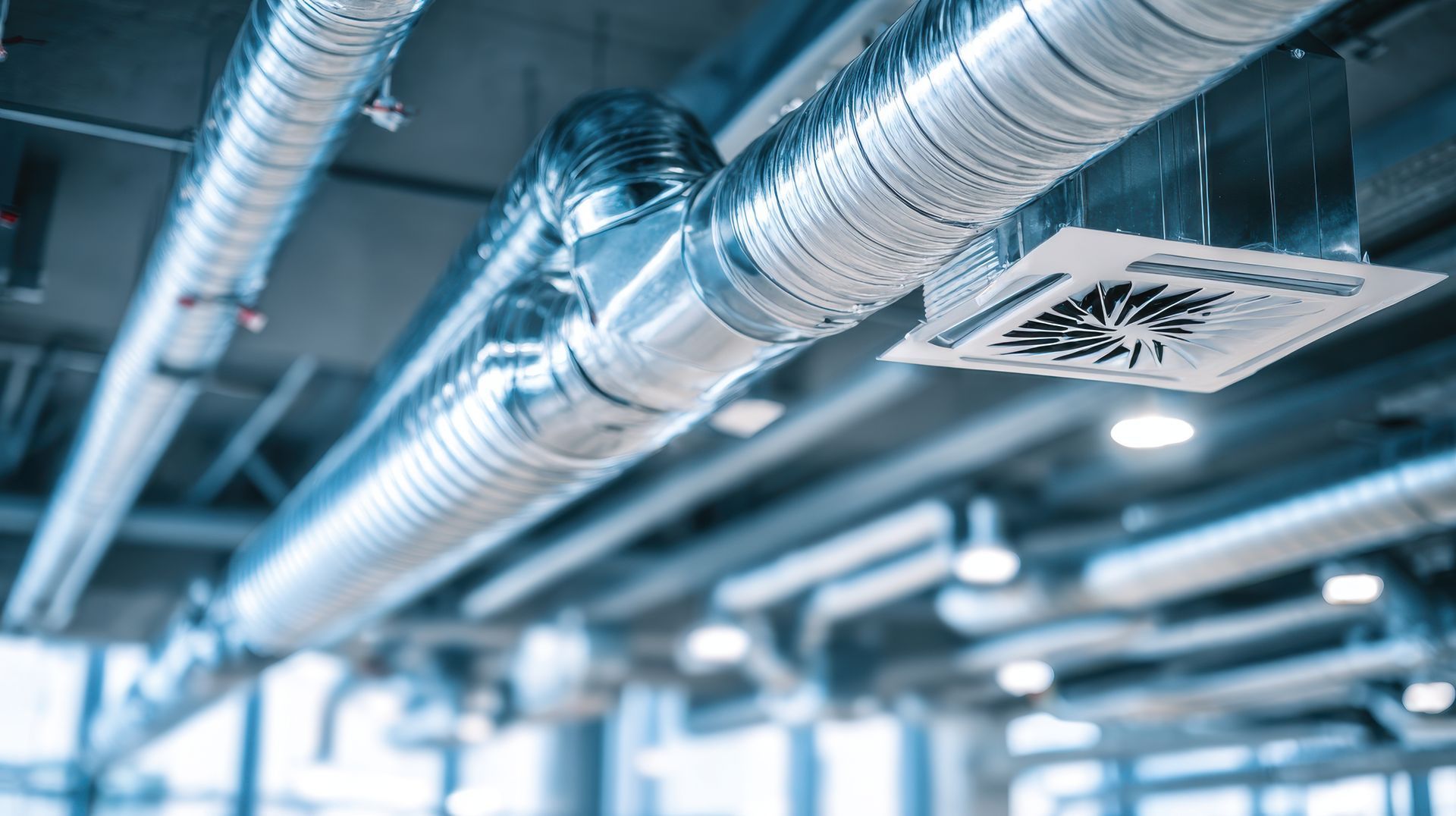 Conduits de CVC et luminaires au plafond d'un bâtiment moderne.