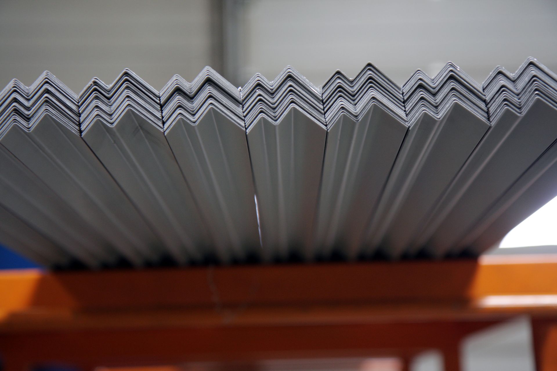 Pile de tôles blanches pliées en zigzag, probablement pour toiture, vue rapprochée.