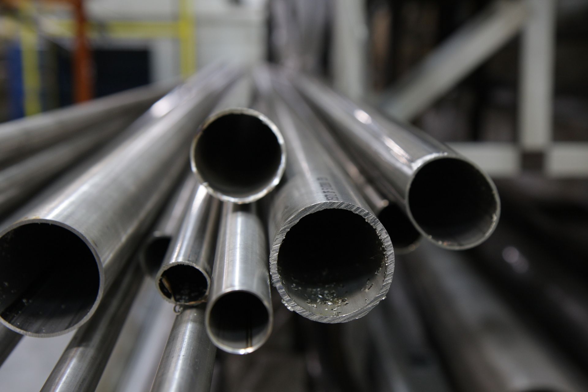 Gros plan de tubes métalliques brillants de différentes tailles, probablement en acier inoxydable, empilés les uns sur les autres.