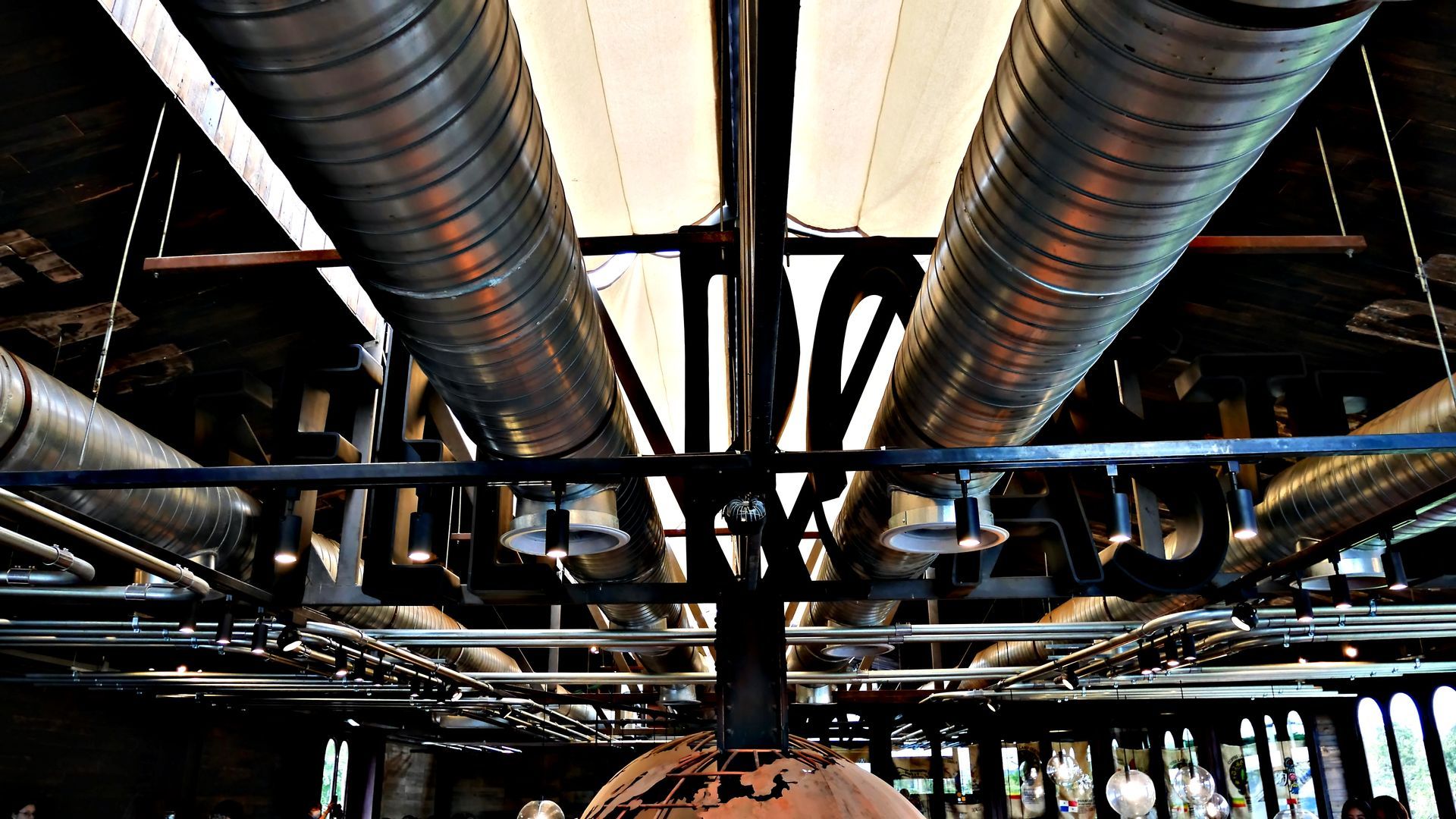 Vue intérieure avec tuyaux de ventilation et éclairage suspendu.