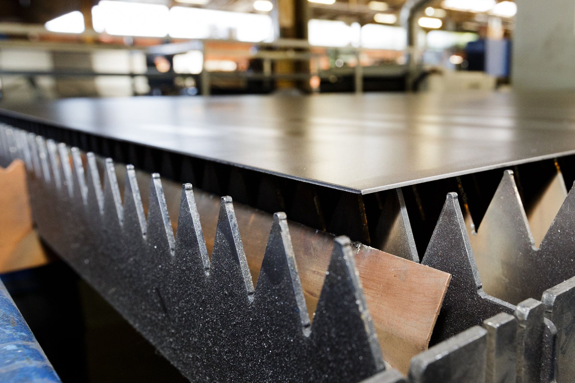 Tôle d'acier sur une table de découpe de métaux, avec une structure de support dentelée en dessous.