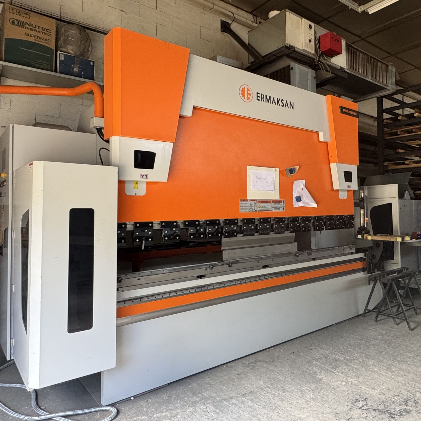 Grande presse plieuse métallique orange et grise dans un environnement d'usine.