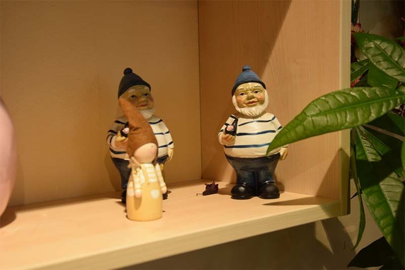 Drei Figuren von Gnomen stehen auf einem Regal neben einer Pflanze