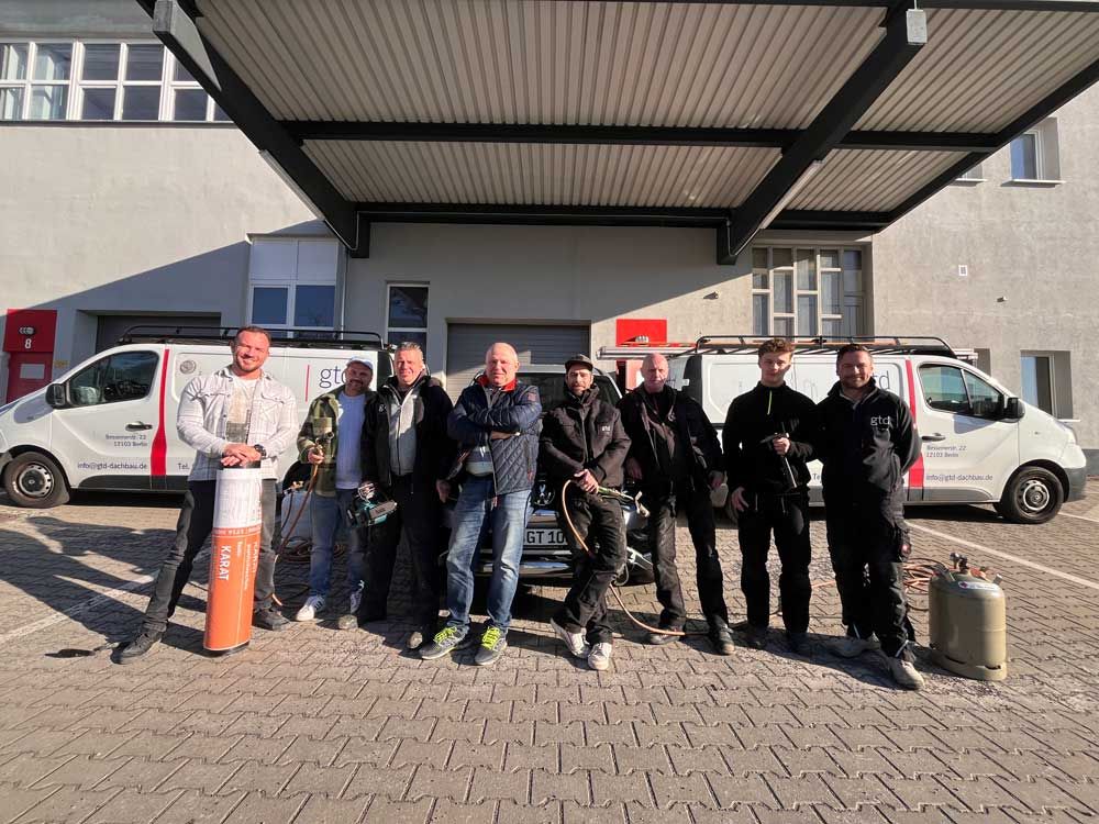 Eine Gruppe von Männern steht nebeneinander auf einem Dach.