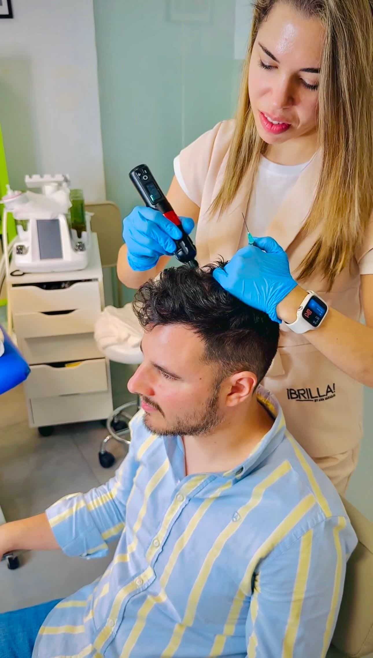 Mujer con guantes utilizando un dispositivo en el cuero cabelludo de un hombre, posiblemente para tratamiento del cabello; entorno clínico.