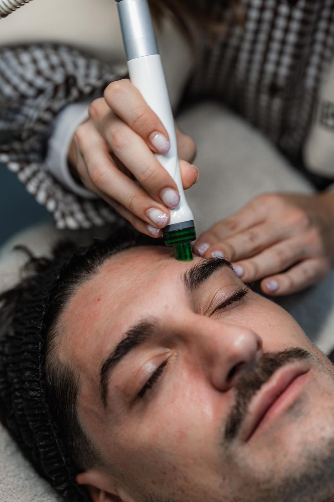 Persona que recibe tratamiento facial con dispositivo cerca de la ceja.