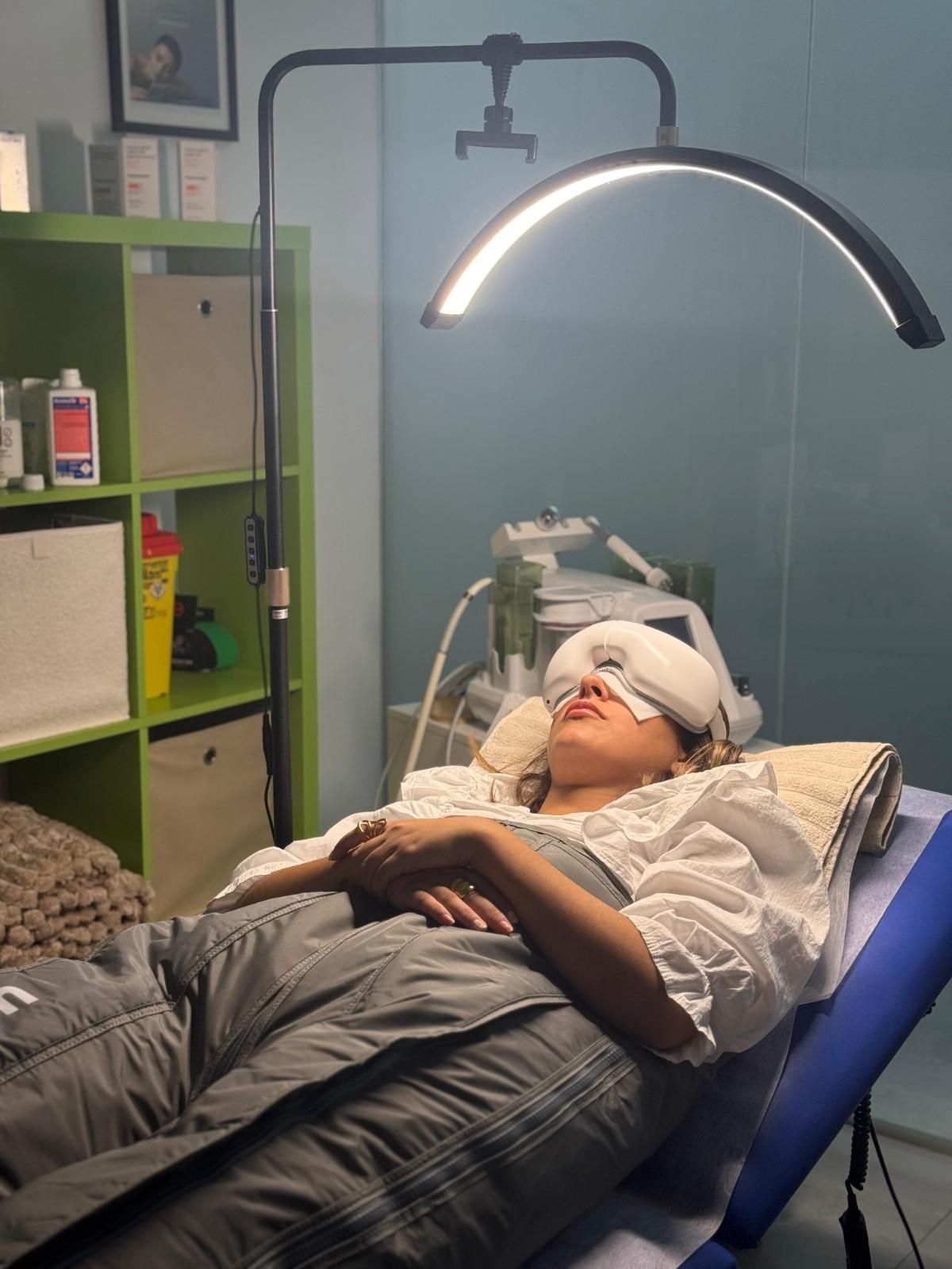 Mujer recibe tratamiento facial bajo luz LED curva en un spa.