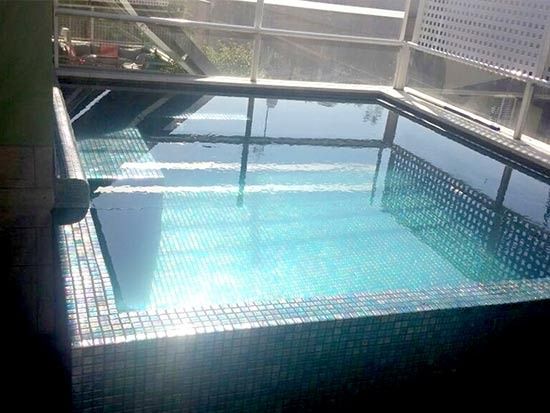 Una piscina con el reflejo de un edificio en ella.