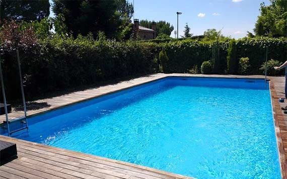 Una gran piscina con agua azul y una terraza de madera.