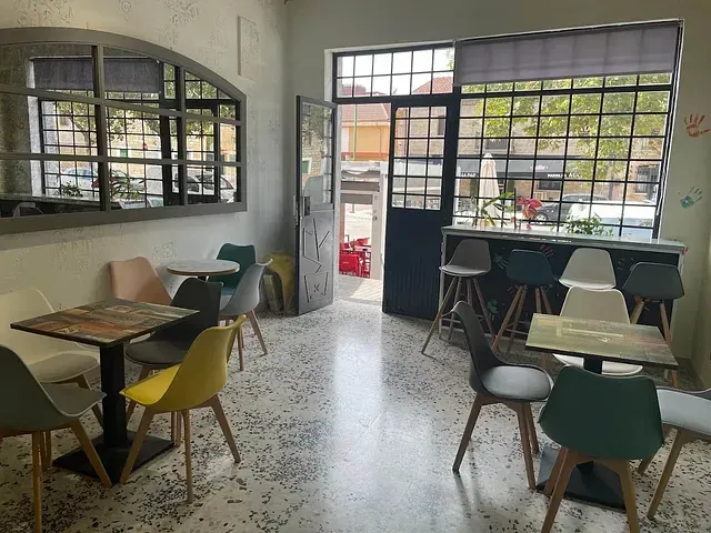 Un restaurante con mesas y sillas frente a una ventana.