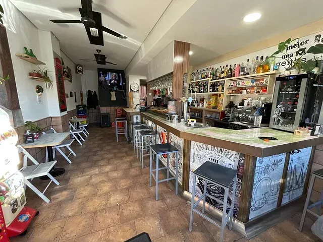 Un bar con mesas y sillas y un ventilador de techo.