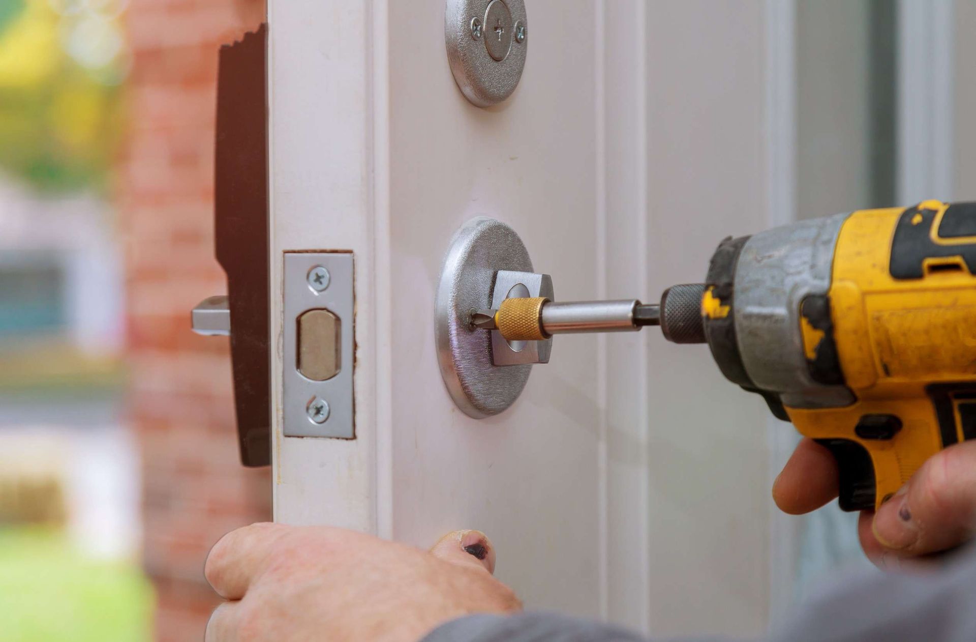 Una persona está instalando una cerradura de puerta con un taladro.