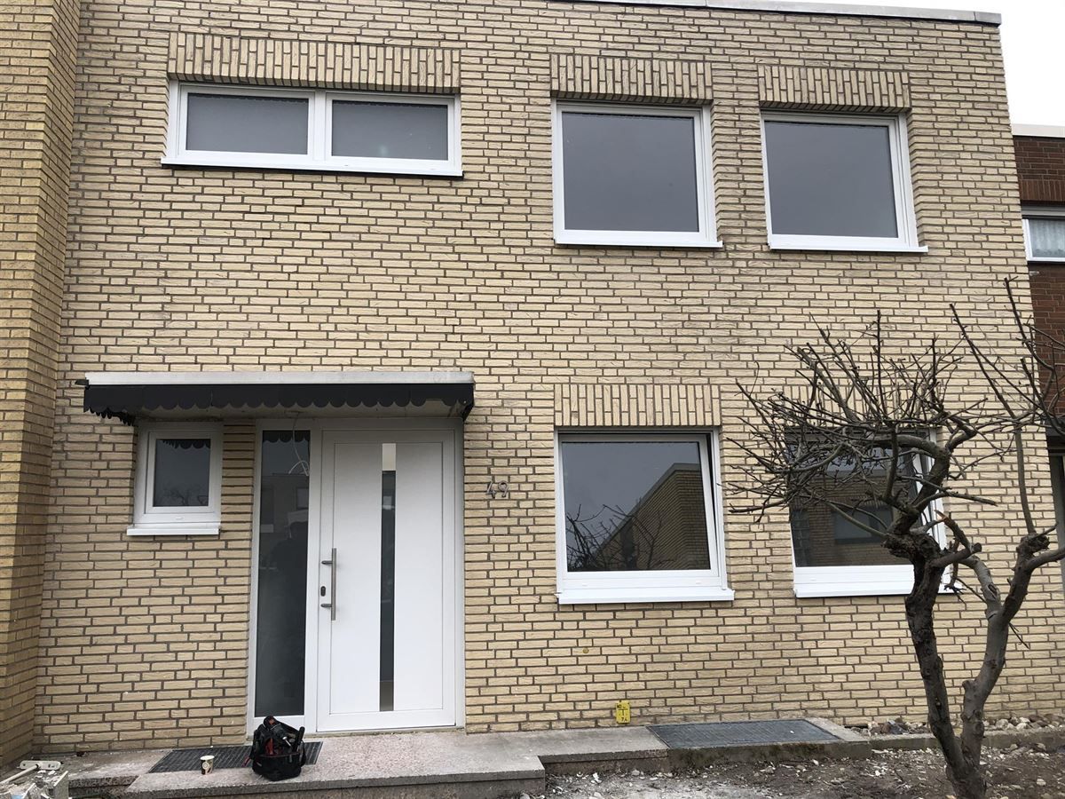 Ein Backsteinhaus mit einer weißen Tür und Fenstern