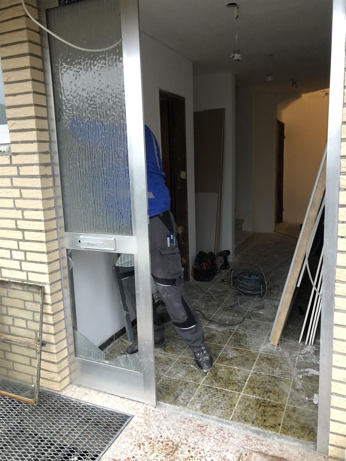 Ein Mann steht vor einer zerbrochenen Glastür.