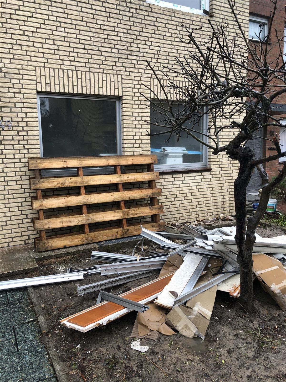 Vor einem Backsteingebäude liegt ein Müllhaufen.