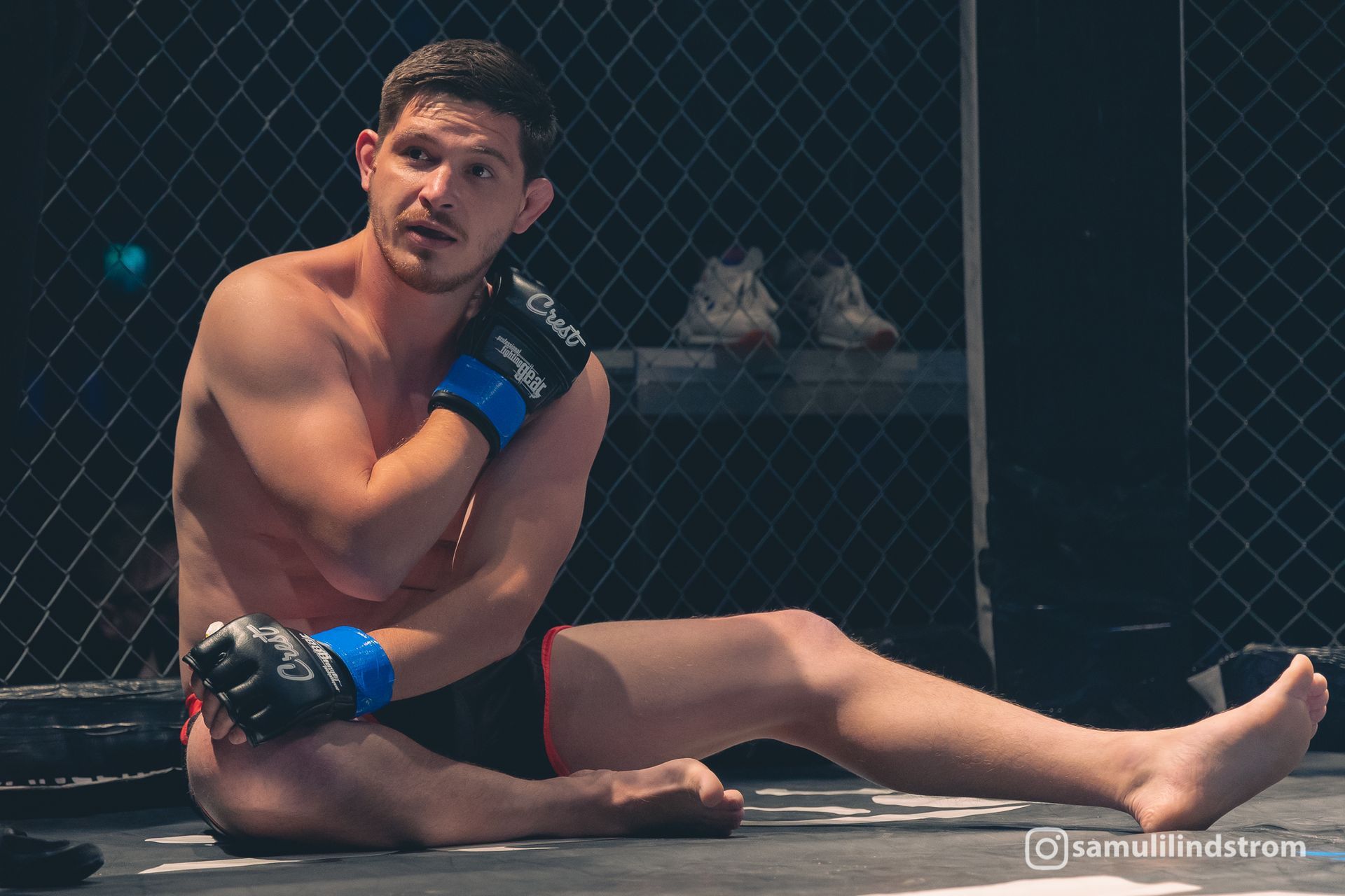 MMA-ottelija istuu matolla häkissä ja pitää kädestään kiinni tuskaisen näköisenä ottelun jälkeen.