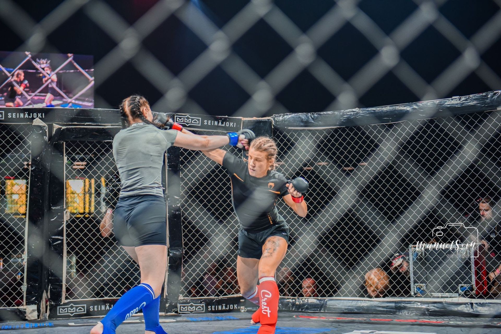 Kaksi ottelijaa MMA-häkissä, toinen antaa korkean potkun ottelun aikana