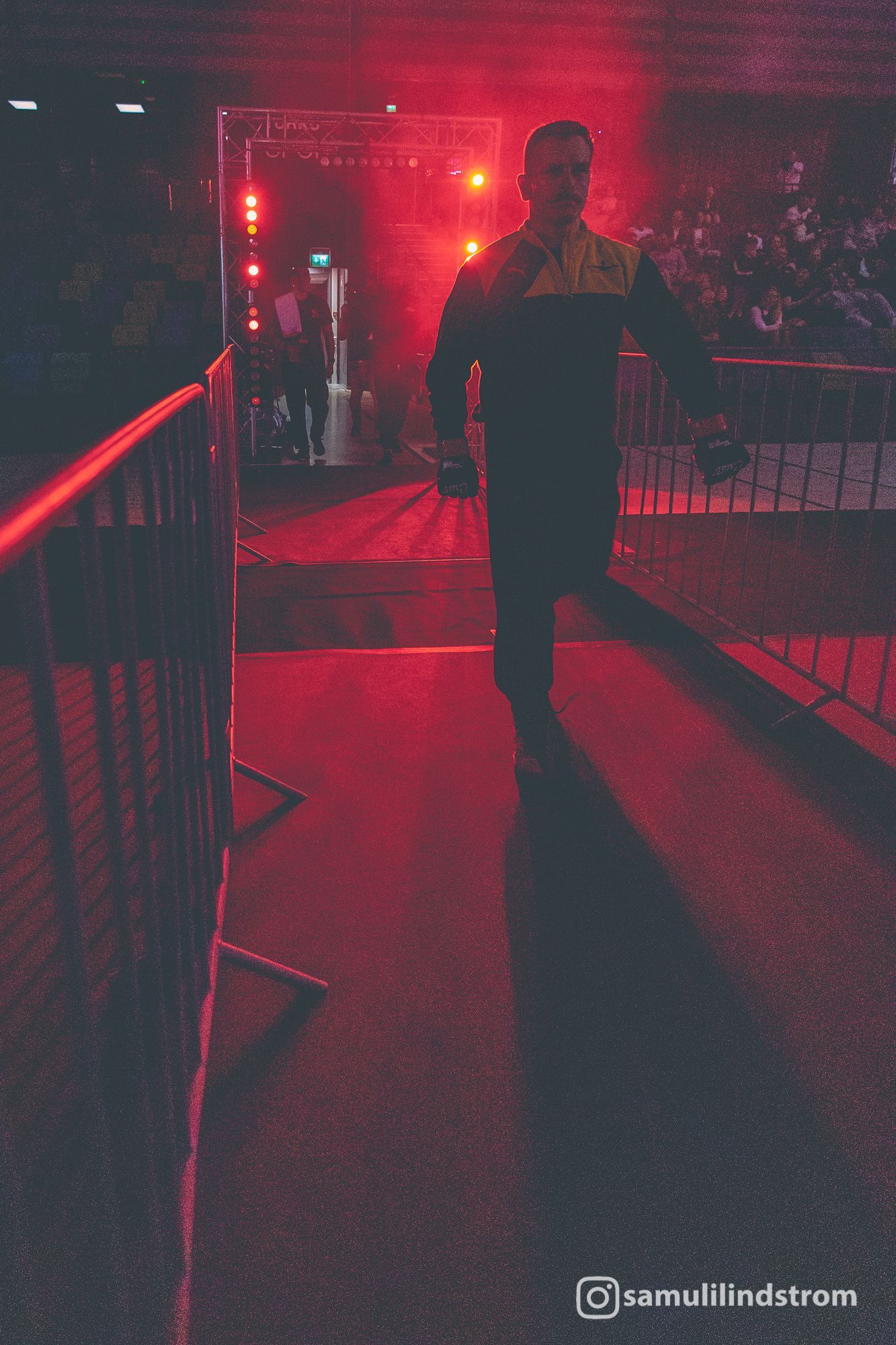 Henkilö kävelee punaisella valaistua käytävää pitkin konsertissa tai tapahtumapaikalla