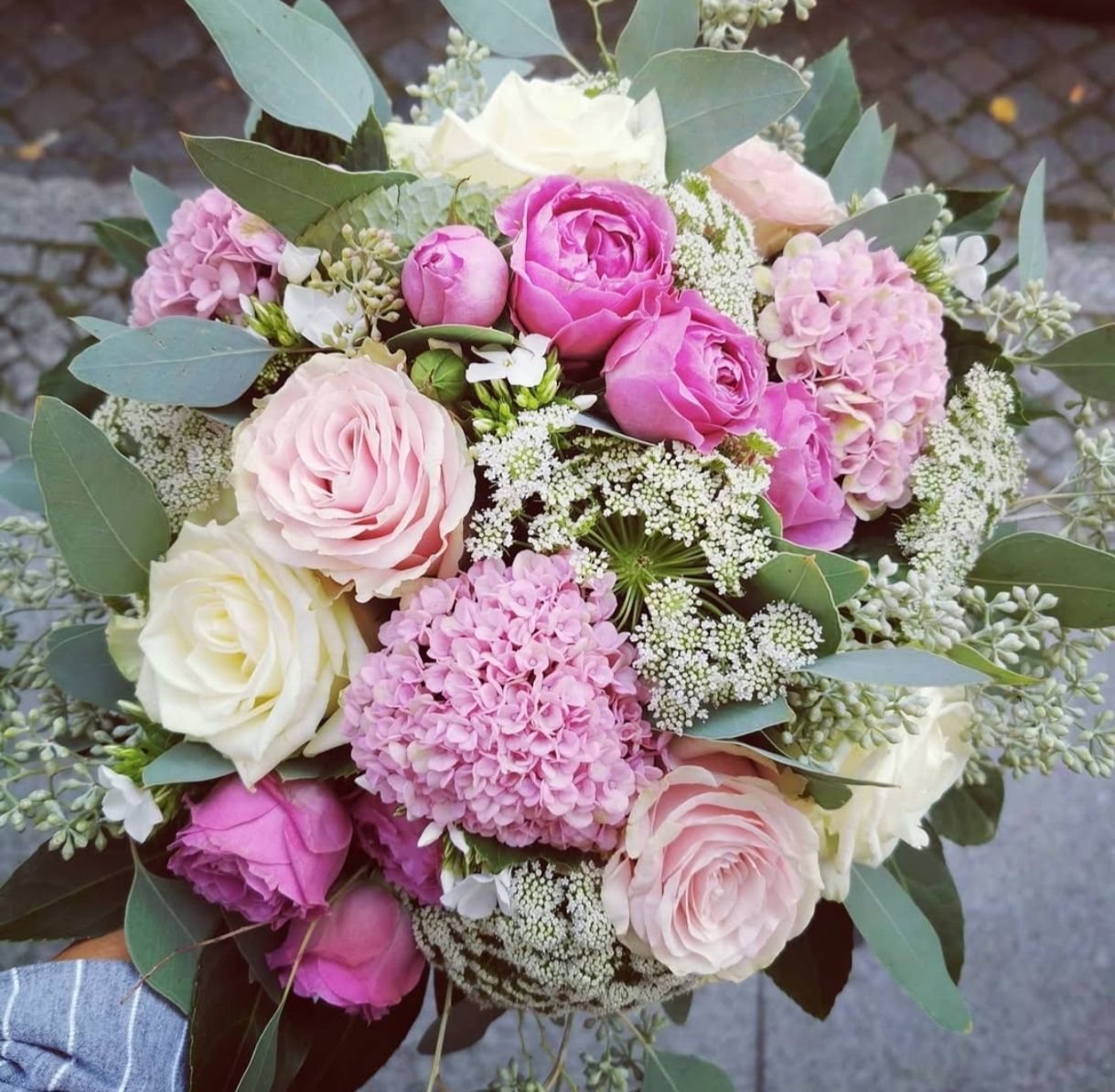 Ein Strauß aus Rosen, Chrysanthemen und Nelken mit grünem Eukalyptuslaub.