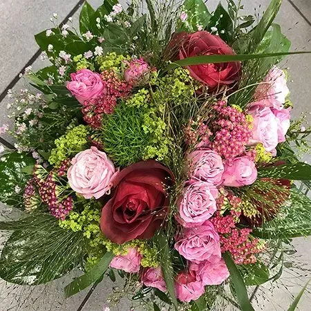 Ein Strauß aus rosa und dunkelroten Rosen mit Grün und kleinen rosa Füllblüten