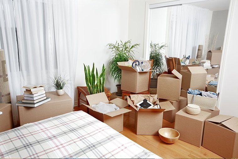 Un dormitorio lleno de cajas de cartón y una cama.