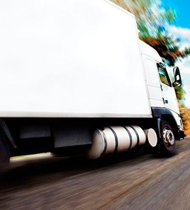 Un camión semirremolque blanco circula por una carretera.