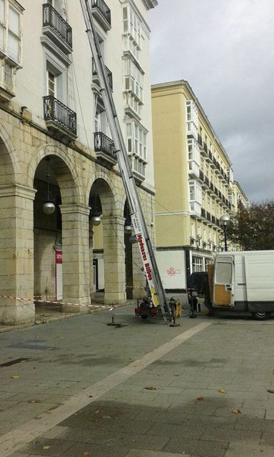 Una camioneta blanca está estacionada frente a un edificio alto