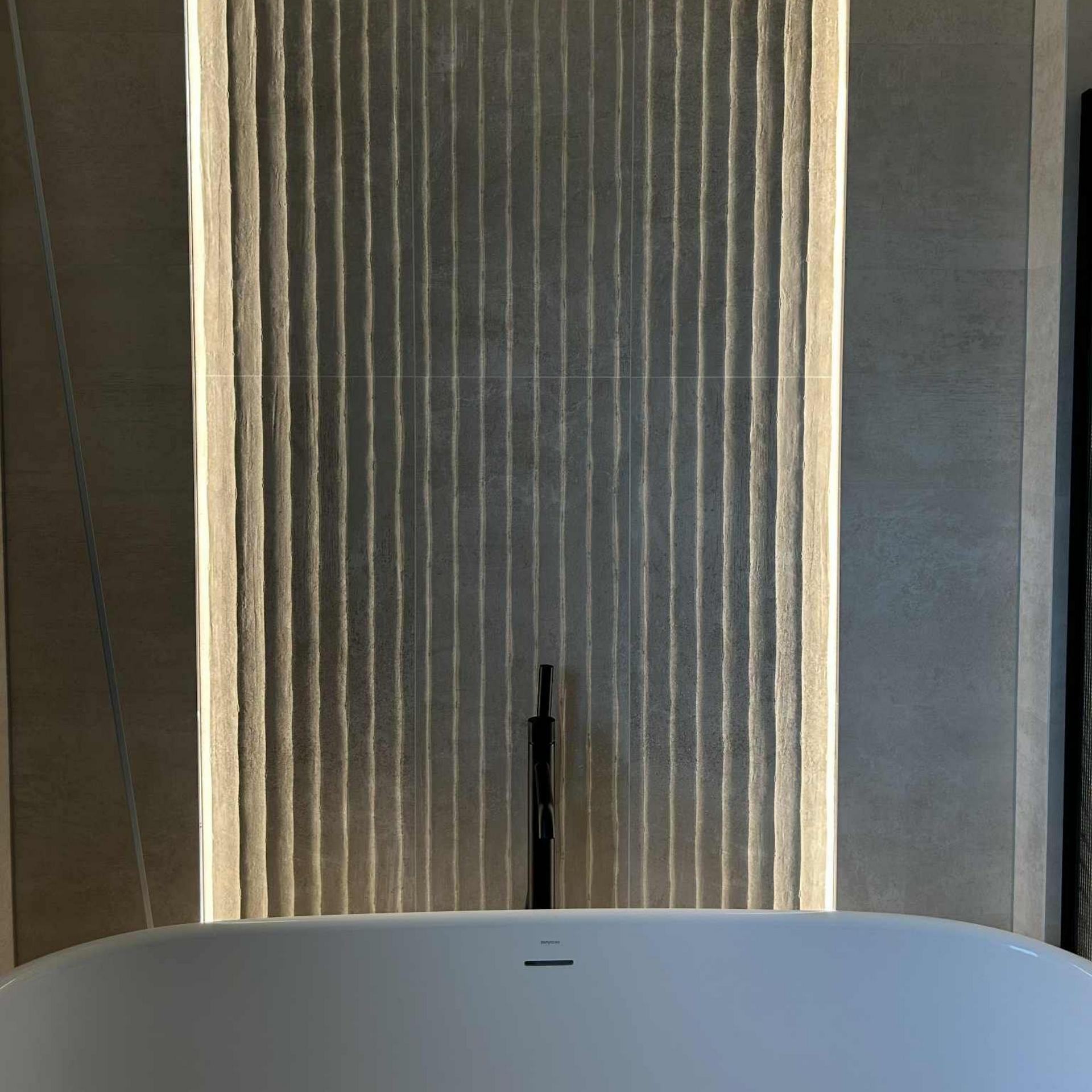 Baignoire sous un mur vertical texturé avec rétroéclairage.