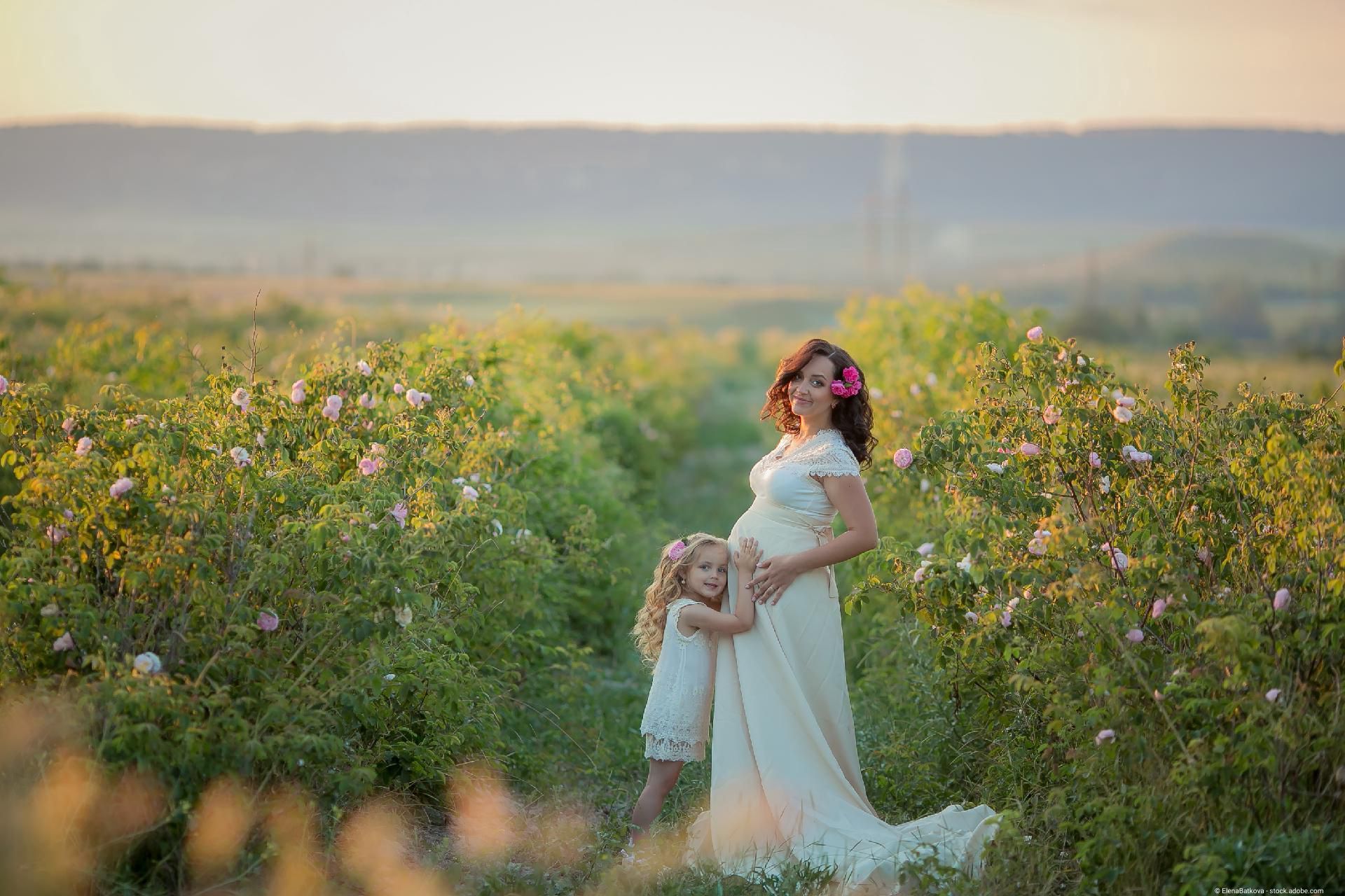 Babybauchfotografie – Schwangere mit Tochter in einer Blumenwiese
