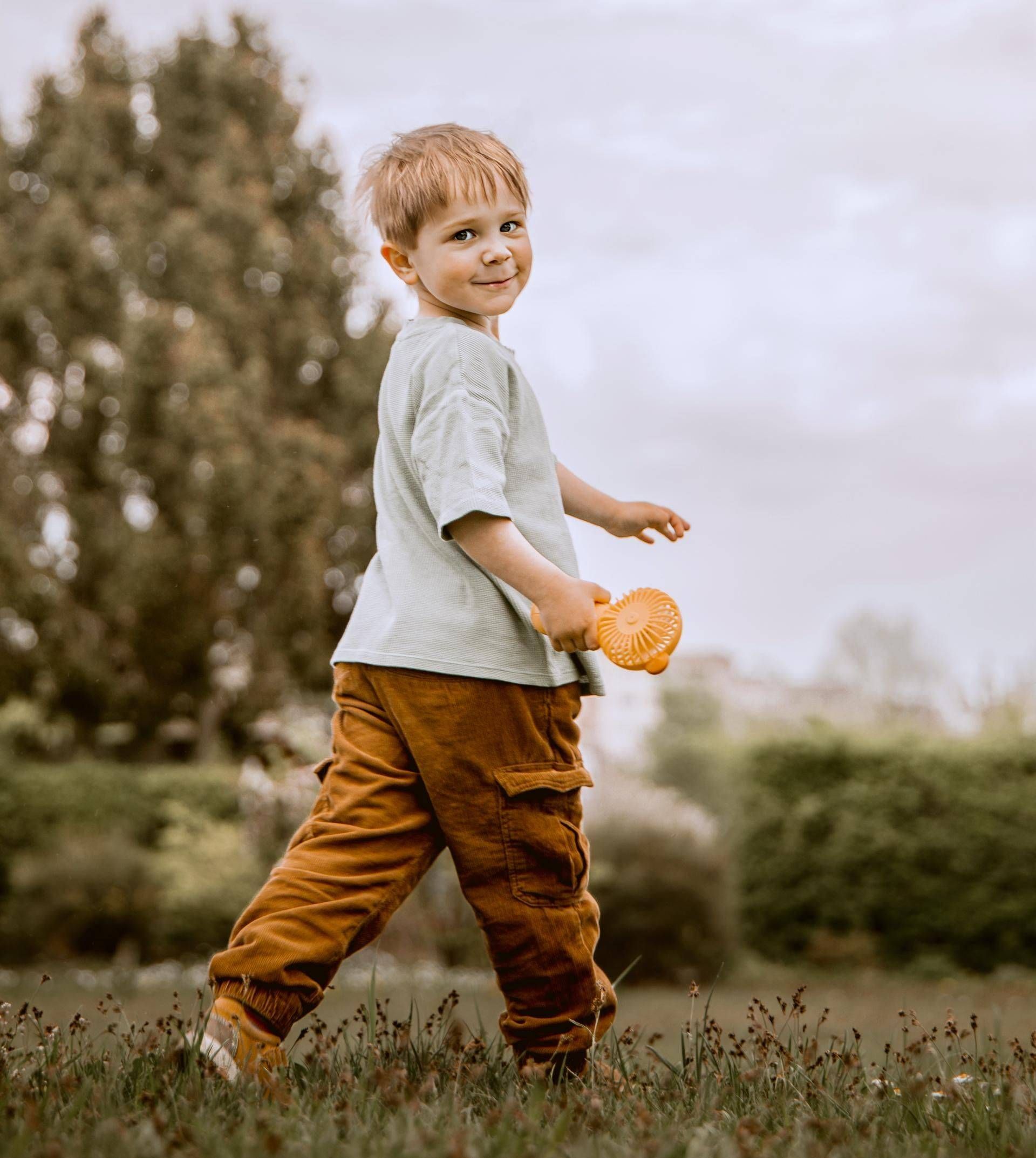 Kinderfotografie – Junge spielt mit Ball im Garten