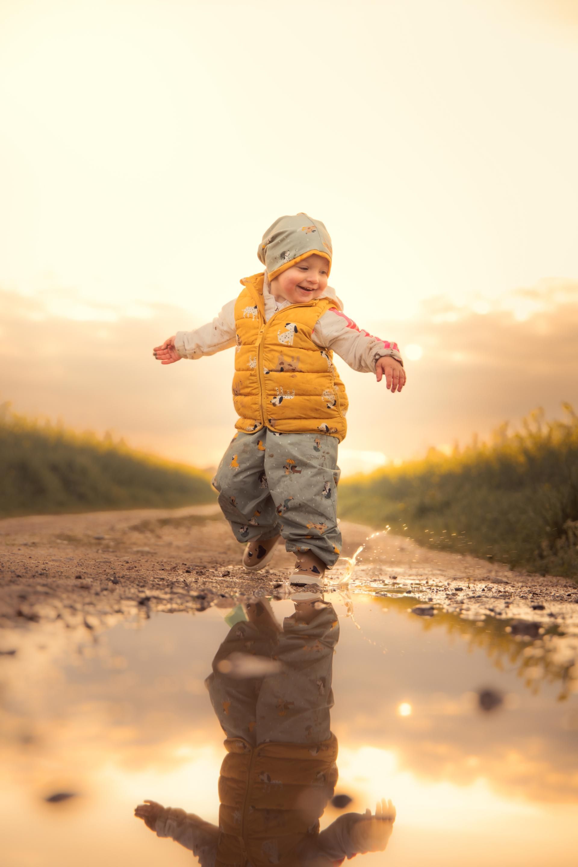 Kinderfotografie – Kind läuft durch eine Pfütze im Sonnenuntergang