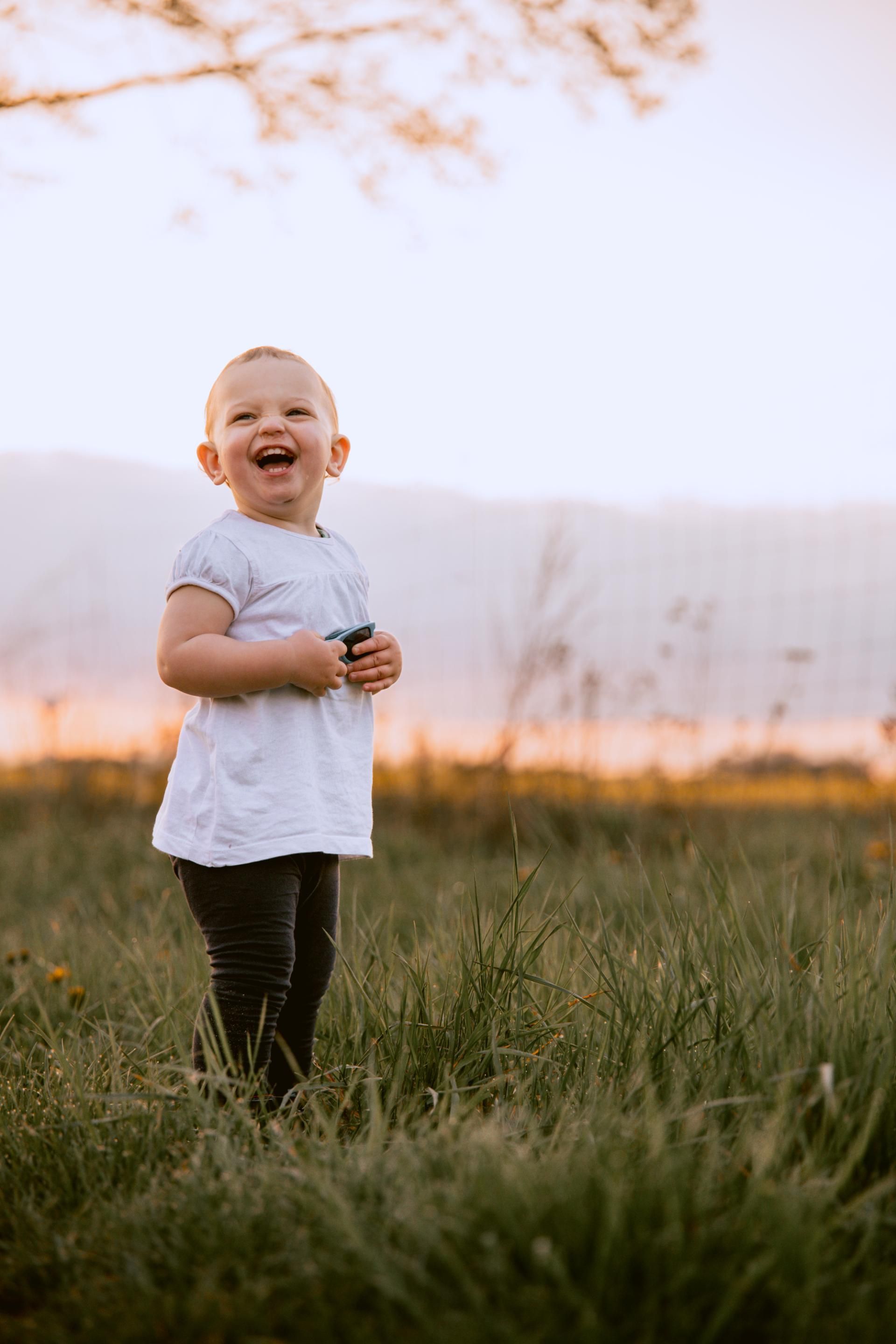 Kinderfotografie – Junge sitzt lachend auf einem Waldweg