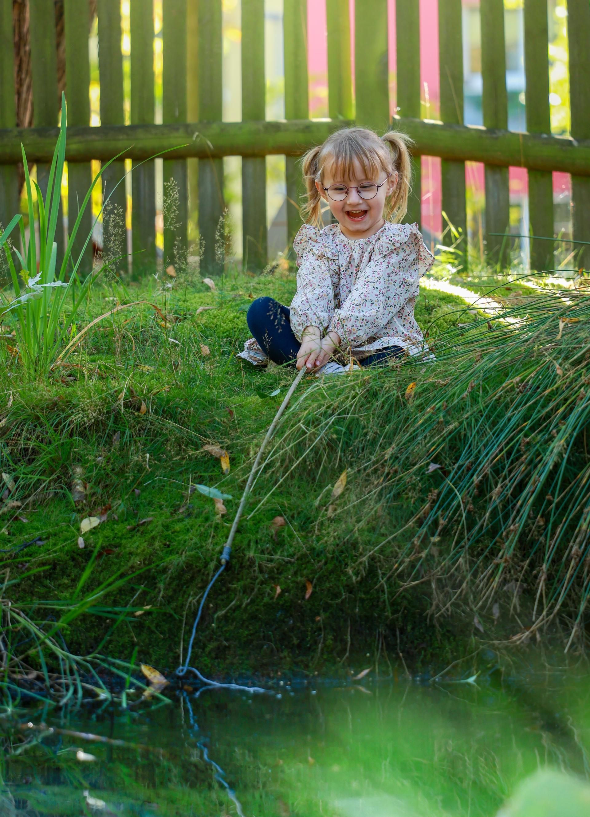Kinderfotografie – Mädchen steht lachend auf einer Wiese