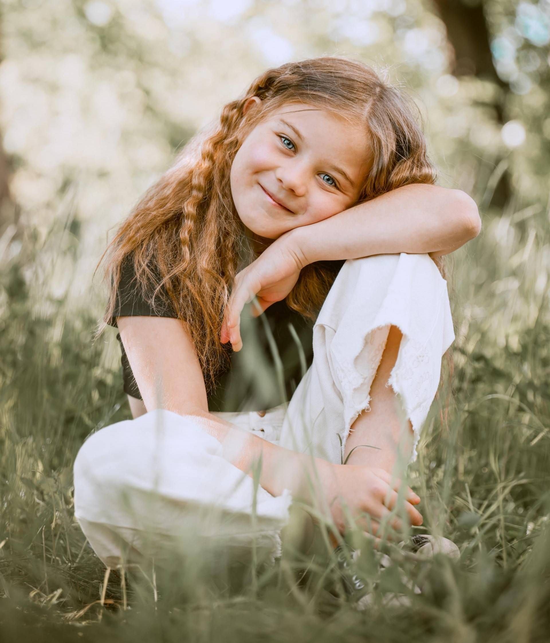 Kinderfotografie – Mädchen lächelt und stützt den Kopf auf die Hand