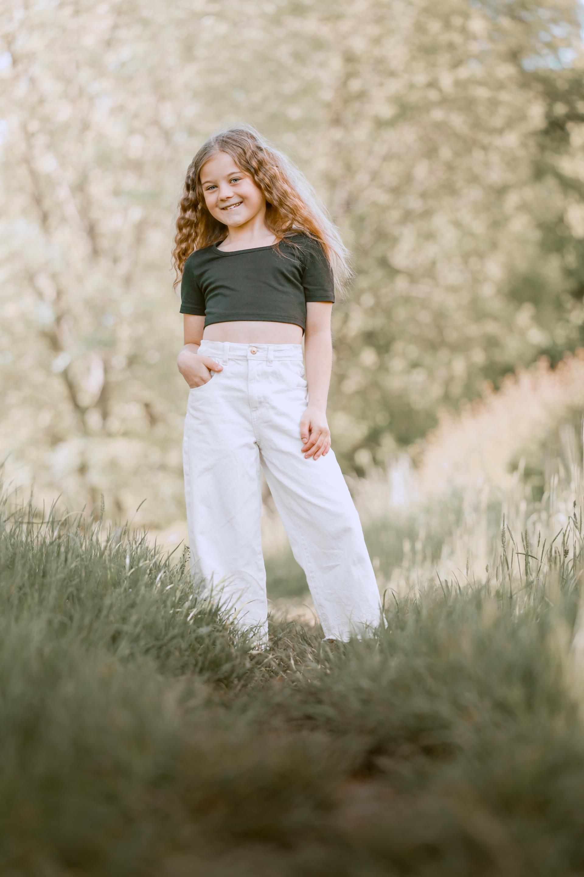 Kinderfotografie – Mädchen steht lachend auf einer Wiese